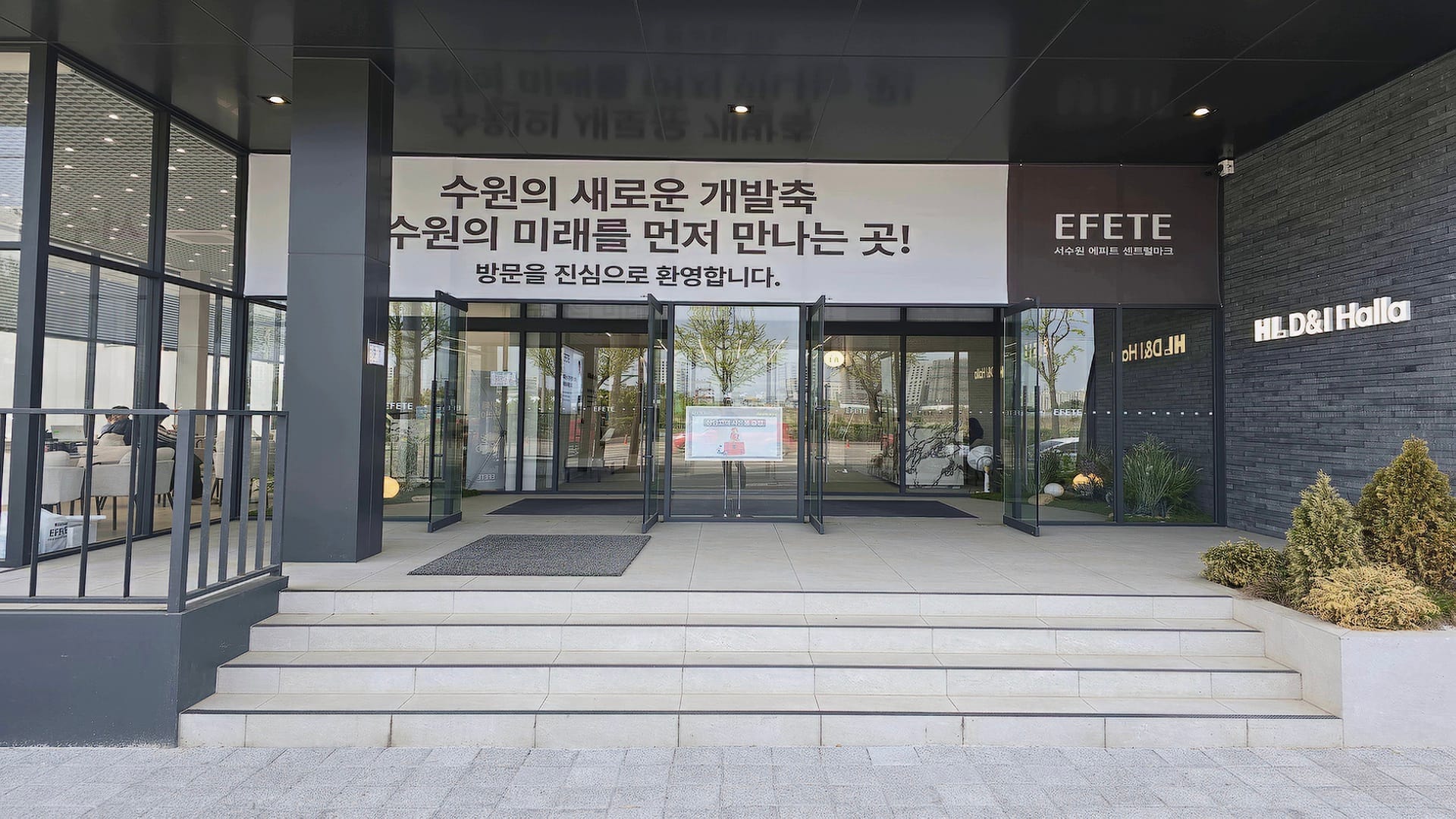 수원의 새로운 개발축이라는 현수막이 걸려 있는 에이치엘디앤아이한라 서수원 에피트 센트럴마크 모델하우스 외부 출입구 모습